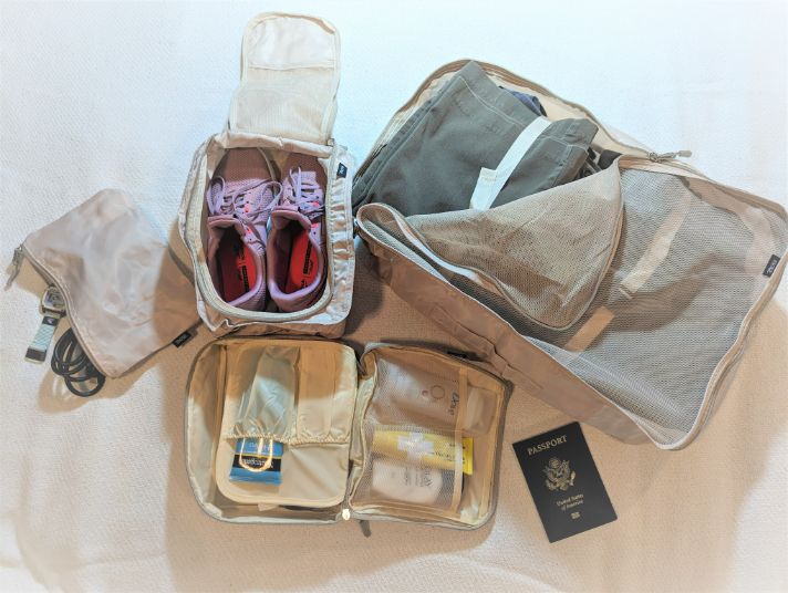 BAGAIL 8-Set Packing Cubes packed and open next to a passport for size comparison