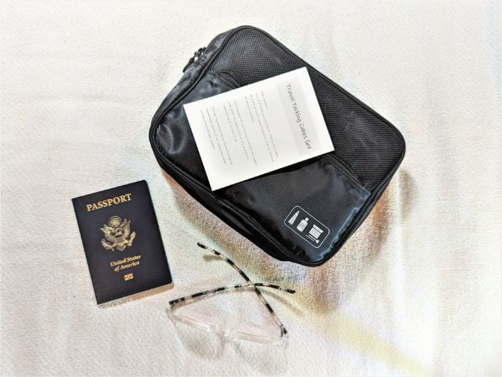 Veken 8-Set Packing Cubes packed into a single cube with instructions next to a passport and pair of glasses