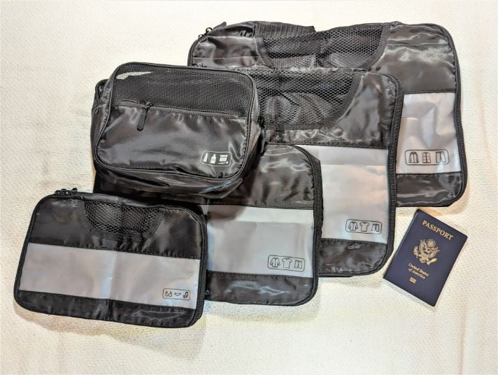 4 of the Veken 8-Set Packing Cubes spread out next to a passport
