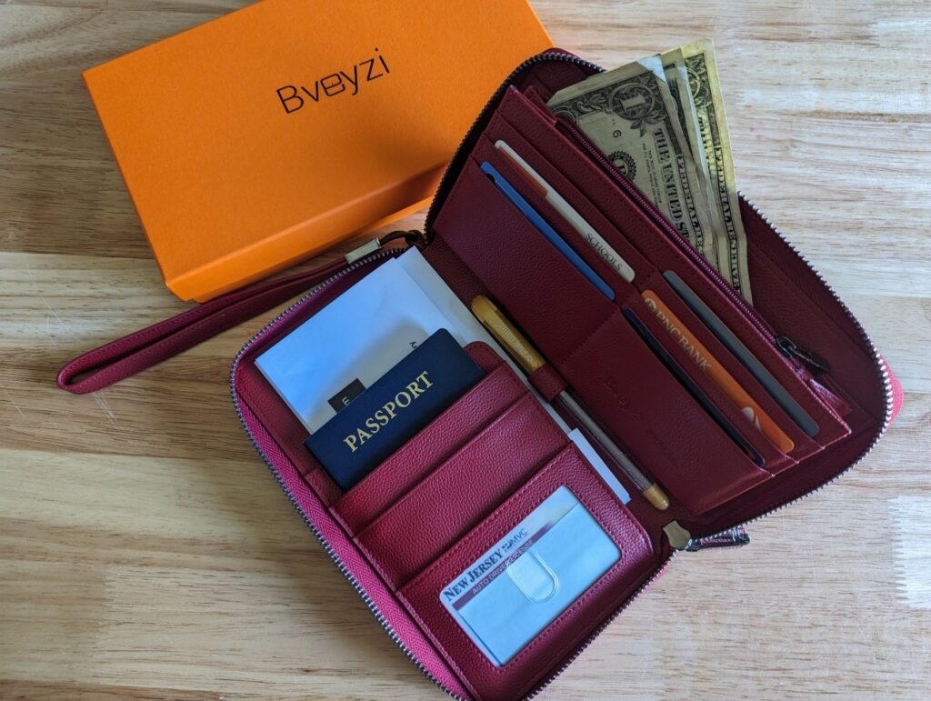 Bveyzi’s Travel Document Organizer wallet open and filled with a passport, travel documents, credit cards, cash, and a GPS tracker