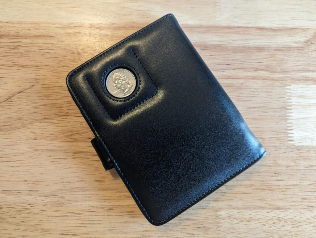 PASCACOO AirTag Passport Holder Wallet closed with a quarter showing scale